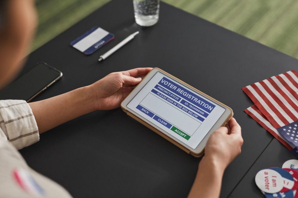Eleitor deve confirmar endereço da seção antes do segundo turno, alerta TSE Pessoa usando um tablet durante um procedimento de cadastro eleitoral em ambiente interno.