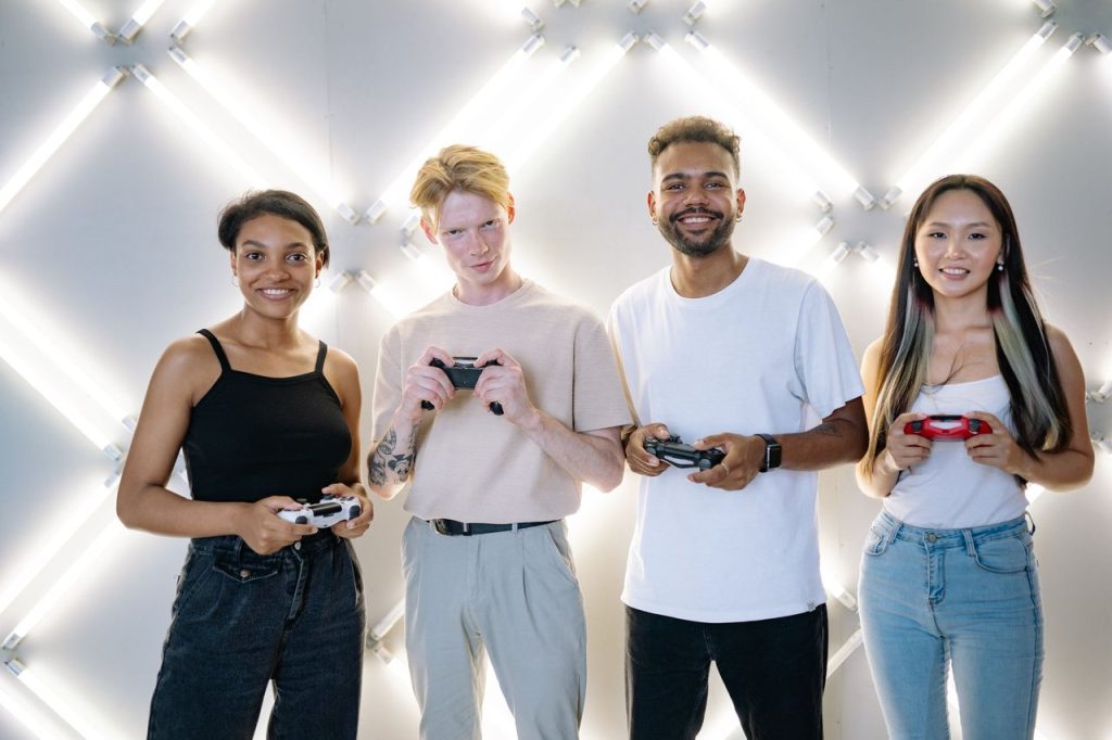 Grupo diverso de jovens segurando controles de videogame em um ambiente interno.